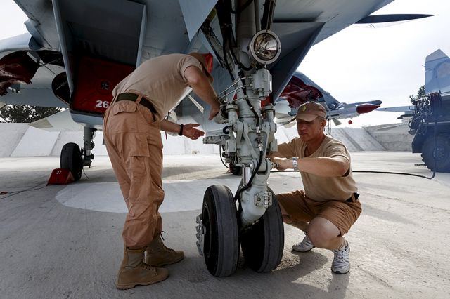 — — - Russian ground staff members work on a Sukhoi Su-30 fighter jet at the Hmeymim air base near Latakia, Syria, in this handout photograph released by Russias Defence Ministry October 22, 2015. (Photo by Reuters/Ministry of Defence of the Russian Federation)