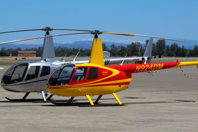 Robinson R-44 (N924DM) - KRDD - 2 of the newer Robinson helicopters parked side by side at Air Shasta. Note the size difference between the R-66 on the left and the R-44 on the right. click full