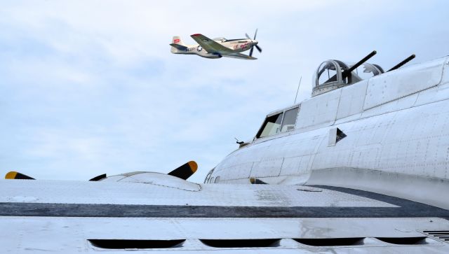 Boeing B-17 Flying Fortress (N3193G) - The Betty Jane P51D (N10607) flying over the parked B17 Yankeey Lady.