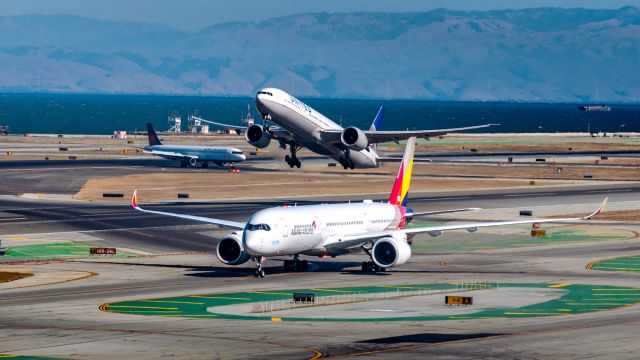 Airbus A350-900 (HL8382) - Three-in-one at KSFO! An Asiana A359 holds short on a taxiway while a United B77W rotates off of RWY 28L. In the background, a smaller Air Canada A321 watches the two heavies in action.