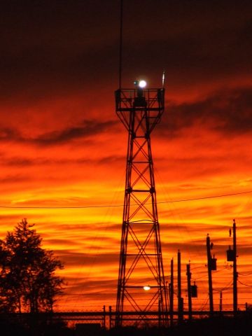 — — - Sun setting behind the airport beacon