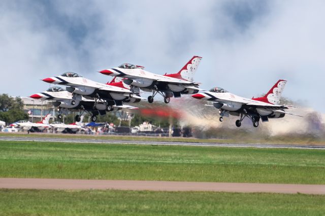 Lockheed F-16 Fighting Falcon — - The four primary Thunderbirds are seen here, just taking off in tight formation to start their performance at the 2022 Sun N Fun air show in Lakeland Florida. I find it fascinating how the commander is the only one watching where they are going and the other three pilots are simply concentrating on the aircraft next to them. In the background you can see two parked Thunderbirds. I have to assume those are numbers 7 and 8, as 5 and 6 were taxiing the runway as 1-4 were taking off. I shot this with my Canon 100-400 IS II lens at the focal length of 248mm. Camera settings were 1/8000 shutter F 5, ISO 800. Please check out my other aviation photography. Votes and positive comments are always appreciated. Questions about this photo can be sent to Info@FlewShots.com