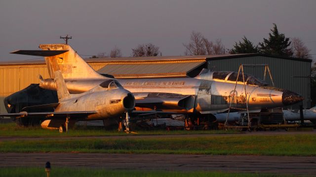 — — - The "Bone Yard." A North American Fury FJ-4, and a McDonald Douglas CF101B (Voodoo) sit next to the Historic Aviation Muesum's hanger awaiting restoration. The F101 must have belonged to the Royal Canadian Air Force as a portion of the Maple Leaf insignia is visible below the crew canopy. Tyler, Texas, 2023