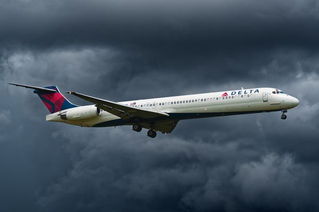 McDonnell Douglas MD-88 (N920DE) - 7/21/2015. Arriving from Atlanta at 2:45pm this was the first aircraft to land on 19R after a small thunderstorm cut across both 19R and 19L approaches. The storms core shown here in the background was impressive, but in the photo it is really about 8-miles away and looks closer because of the telephoto lens effect.