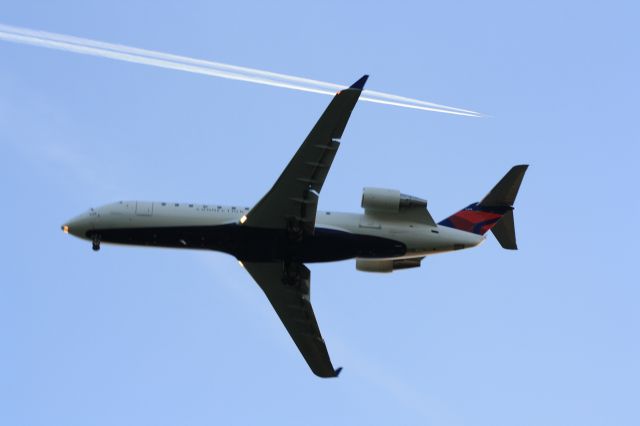 — — - Delta Regional jet on approach to rwy.13,as another jet passes above.