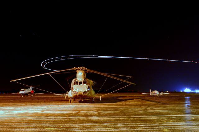 — — - A Boeing CH-47 Chinook Sits on the ramp as a United 757 takes of and turns to the east.