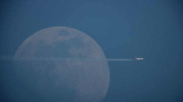 — — - Unknown airline flying past the moon.
