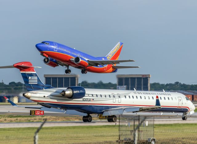 Canadair Regional Jet CRJ-900 (N247LR) - CRJ9 exits runway 4 as a B735 (N510SW)  rockets overhead. Taken in 2014. 