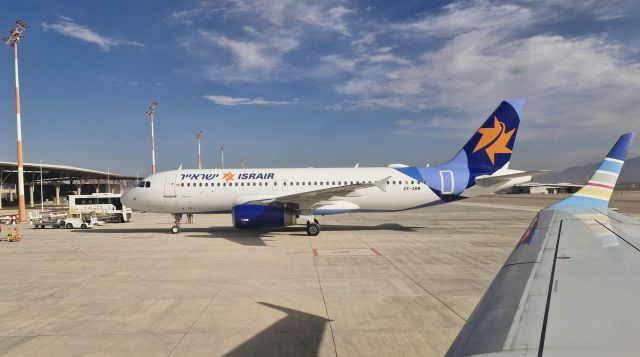 Airbus A320 (4X-ABW) - One comes, one leaves. Israir A320 4X-ABW parks at the stand after landing at Ramon International Airport, while Arkia's  E195 4X-EMC pushes back prior to departing to Ben Gurion International Airport