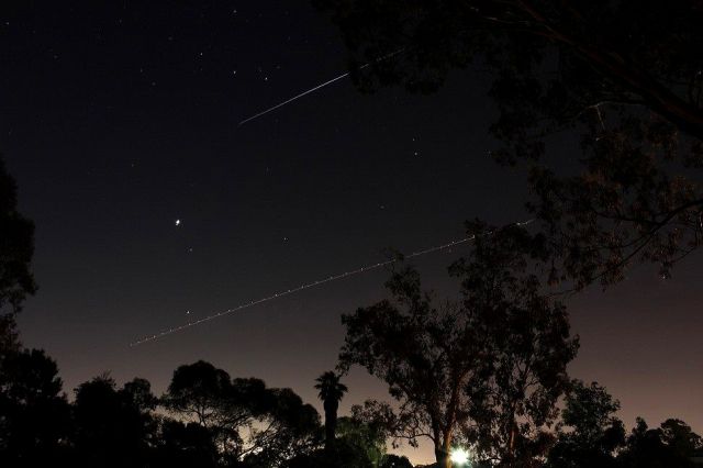 Boeing 737-800 (VH-VXA) - Standing in local park. Picture of the International Space Station near the top, going over Adelaide South Australia, while a Qantas plane is on final approach. It was too dark to see the actual tail number, but VH-VXA is often spotted. 30 seconds exposure on a 550D EFS 18-55 Lens. Not doctored. Still have orig full size pic from the card.