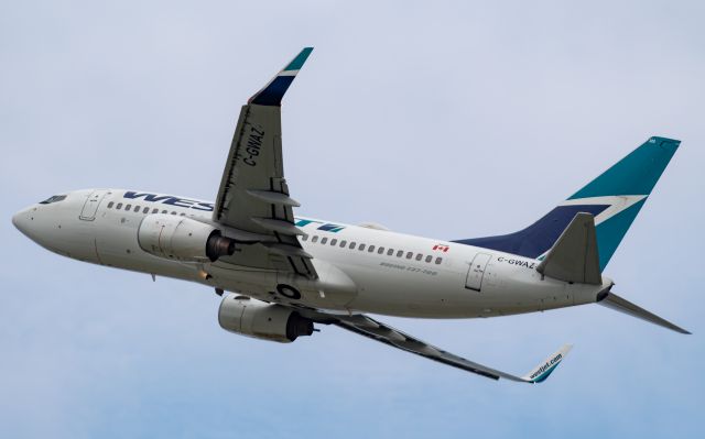 Boeing 737-700 (C-GWAZ) - A WestJet Boeing 737-700 takes to the skies on a cloudy Montreal morning.