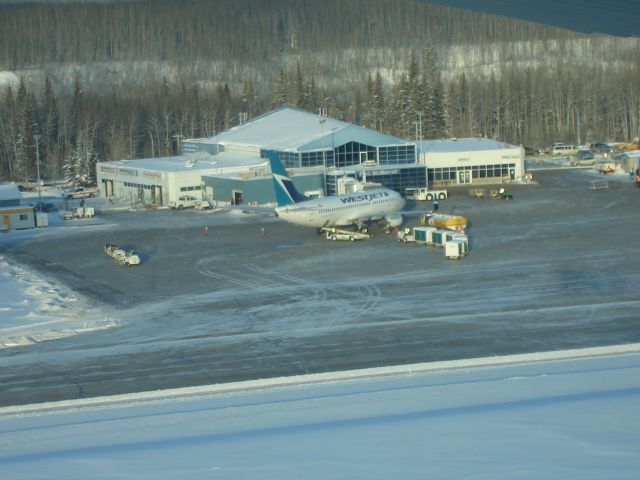 Boeing 737-700 — - Aerial view of a WestJet Boeing 737-700 at the passenger bridge at the Fort McMurray Airport, Alberta Canada on a wintery afternoon.