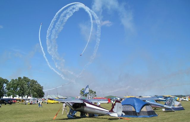 — — - Watching the Aeroshell Aerobatic Team with their T-6s from the Antique/Vintage area of Oshkosh. . 