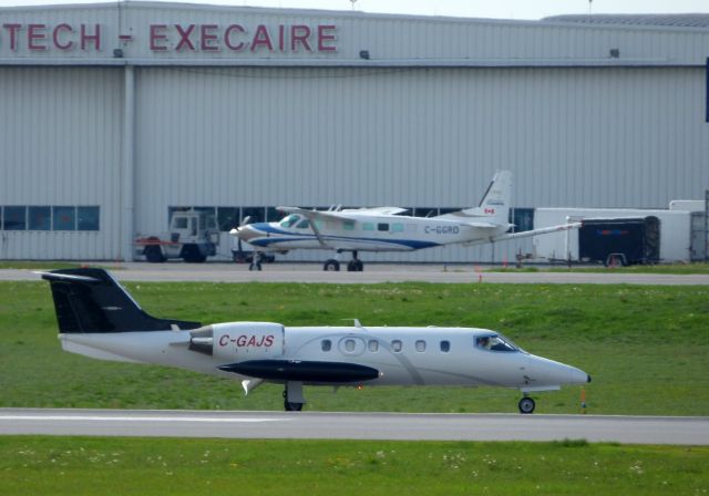 Learjet 23 (C-GAJS) - Shown here taxiing is a 1979 Learjet 23 with that Cessna 208 on the tarmac in the Spring of 2017.