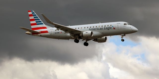 Embraer 170/175 (N211NN) - The dark black storm cloud behind it frames American Eagles N211NN (Compass Airlines - CPZ), an Embraer 175, as it covers the final three thousand feet of its short final approach to Reno Tahoe International.