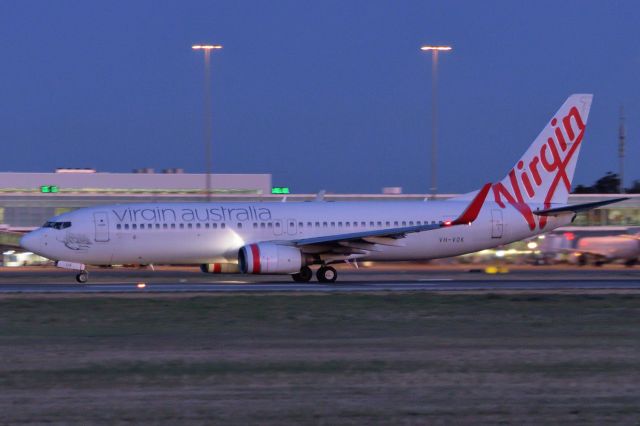 Boeing 737-800 (VH-VOK) - Feb 6, 2020, 0623 hrs, taking off from runway 23.  While sunrise is still about half hour off the pre-dawn glow highlights the silver trim on the Virgin logo on the tail.