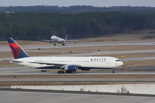 BOEING 767-300 (N125DL) - N125DL taxis to the general aviation terminal as N491UA takes off from runway 23R