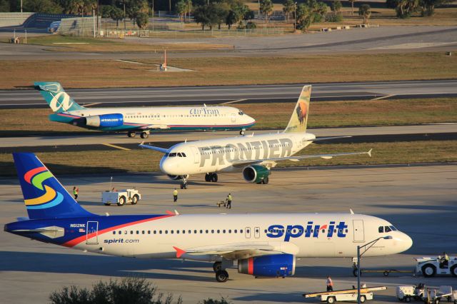 Airbus A320 (N612NK) - A busy period at Earhart terminal. Frontier A.320 N207FR waits for gate access and AirTran B.717 N968AT taxies past to line up for departure.