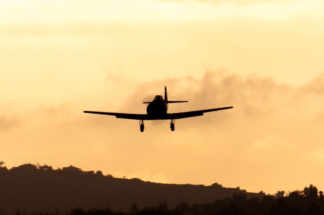 — — - AT-6 Texan comes in to land at sunrise