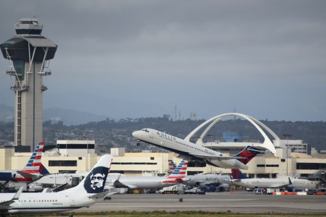 Boeing 717-200 (N974AT) - Great shot with Alaska airlines holding short 25R and the American Airlines terminal in the background. 