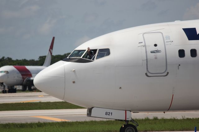 Boeing 737-800 (C-FRWA) - A captain of WestJet Airlines gives a wave at Fort Lauderdale/Hollywood International Airport. In the background you can see a chard Dynamic Airways still sitting after its fire on the runway last year.