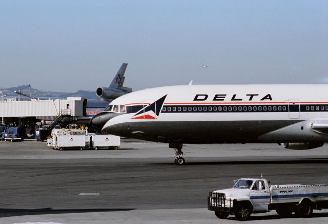 Lockheed L-1011 TriStar (N721DA) - KSFO - Late 1980s at SFO - L-1011 on taxi to the gate. Photo taken from the 1980s Intl Terminal. Hit full for larger view - note the guy in the jump seat,