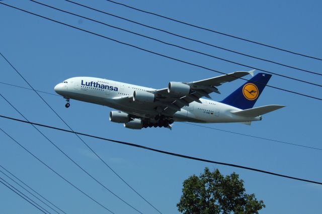 Airbus A380-800 (D-AIME) - While stopped at traffic lights near JFK "Lufthansa 400" passed over on finals for runway 22L. Nicely framed by the overhead cables! 24 August 2015.