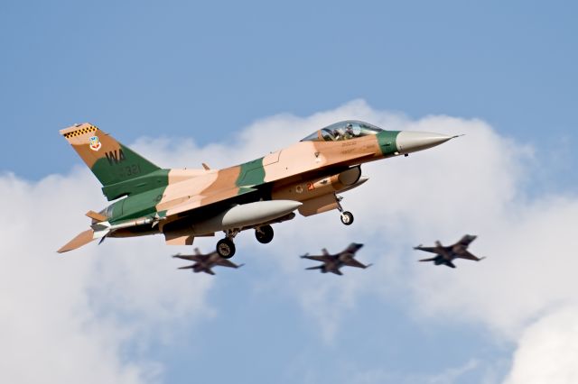 — — - Aggressor F-16 pre[ares to land while three others make a pass at Red Flag, Nellis AFB