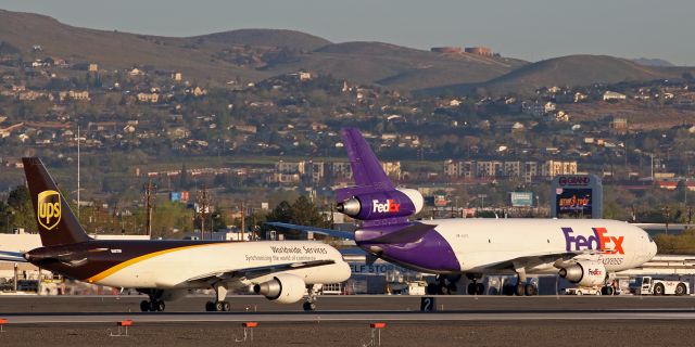 Boeing 757-200 (N407UP) - UPSs N407UP, a B752, rolls north on Bravo taxiway while, just behind it, FDXs "Sharrese (N311FE), a DC-10, is being disconnected from the bar after being pushed back on to Alpha taxiway as both cargo birds are about to make morning departures from Reno.