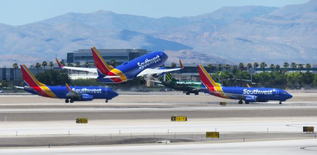 Boeing 737-700 (N563WN) - Southwest Boeing 737s X 3 at KLAS Las Vegas. 2 Arrivals while 1 is departing. Special livery PTFC Alaska Airlines 737 also in the background ;) 