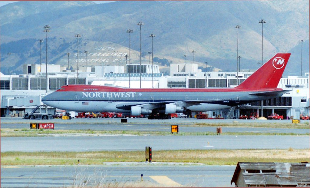 — — - KSFO - Northwest 747 being tugged over to a remote slot for the day - this is LN: 163 and flew with NWA until about 2002. This photo date approx June 1997 and you can see the new Terminal is not yet built but ground clearing was underway, The new SFO terminal opened in Dec 2000. This photo from near or at the Millbrae Ave Airpark adjacent the 1R departure Runway.