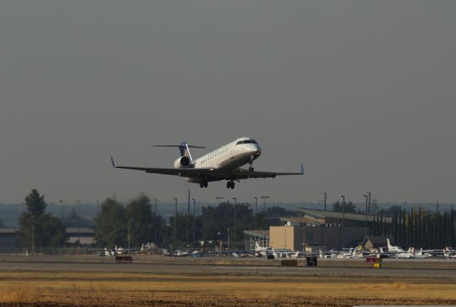 Canadair Regional Jet CRJ-200 (N939SW) - KRDD - Skywest RJ departing Runway 34 at Redding for San Francisco with the usual summer murky sky due to forest fires burning in the north state. The Redding terminal is visible in the background and has an odd shaped roof that makes it look like the building is rotating out from the front parking area. Photo date Sept 17th, 2017.