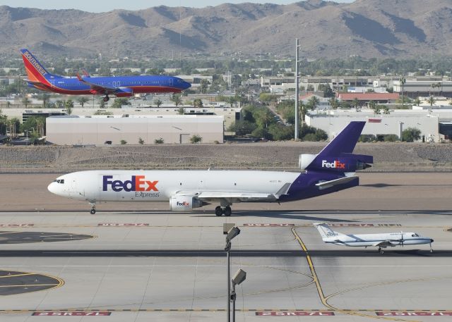 Boeing MD-11 (N612FE) - N3052K is on their take-off roll from 25R. N612FE is on taxiway F to the active and N8314L is on short final for 25L.