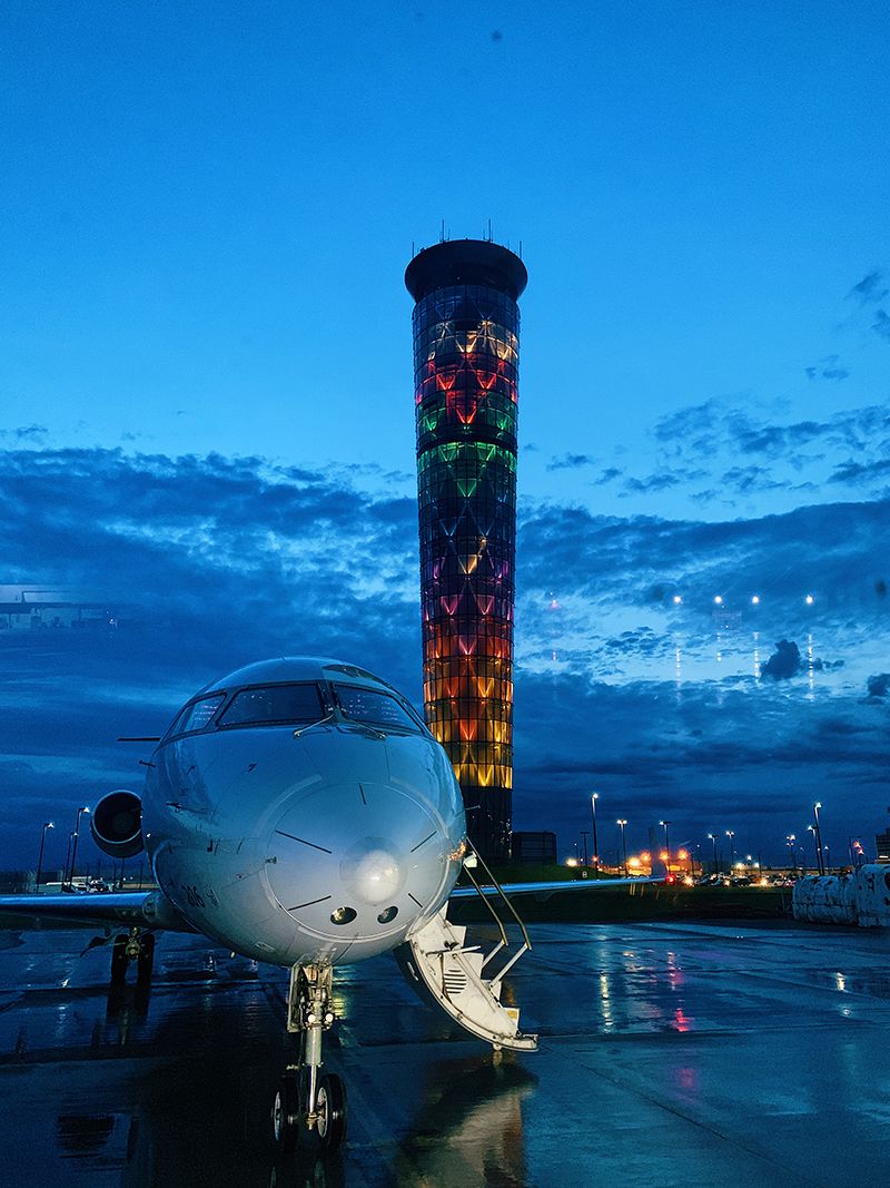 Canadair Regional Jet CRJ-200 (N206PS) - Dayton International Airport's Air Traffic Control Tower all lit up behind N206PS early in the morning.