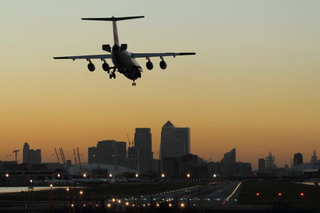 — — - London City Airport at dusk, as a landing BAe-146 deploys it's airbrakes.