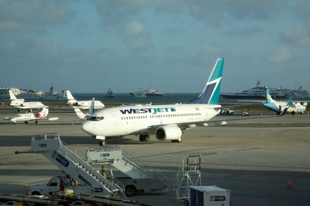 Boeing 737-700 (C-FLWJ) - West Jet Boeing 737-700 is caught in late sunshine awaiting a skybridge - and against a background of superyachts - in Sint Maarten, 6 Jan 2013