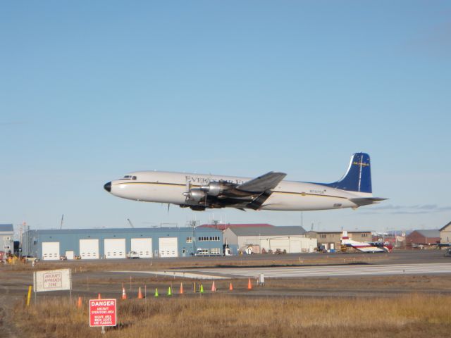 Douglas DC-6 (N747CE) - Everts Air Fuel taking off on runway 27. Notice he is over the threshhold bars for runway 09. There is a public road 50 in front of him. Kotzebue Alaska 10.07.2010