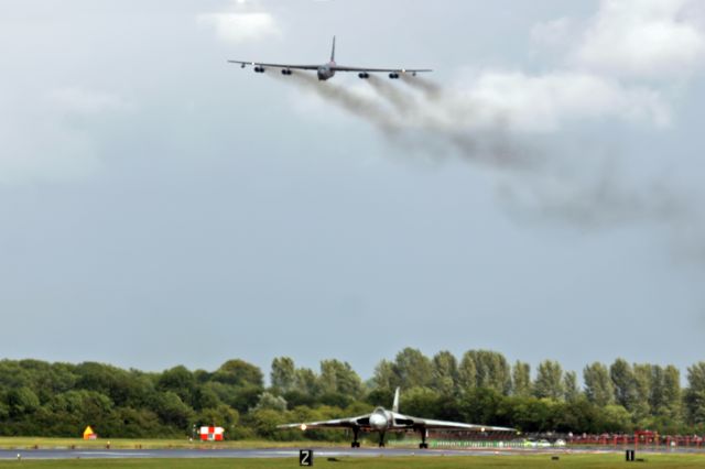 Boeing B-52 Stratofortress — - An RAF Vulcan on the runway at Fairford, UK, as a Buff flies overhead.