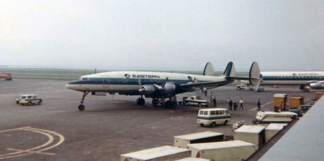 Lockheed EC-121 Constellation — - Scan of a Kodak 620 film picture taken at Logan (KBOS) on a Kodak Bullseye camera in 1968 captures passengers deplaning from an Eastern Lockheed Constellation after arriving at Boston on one of the hourly LGA-BOS shuttle flights.  On this particular day, the Connie was a substitute, "filling in" for the Electras that were the normal equipment EAL used on the shuttle runs that year.br /As best as I am able to determine after looking thru the FA photo gallery, this is the first post in the FA gallery that shows an EAL Connie in the "hockey stick" livery.  There are other pics of Eastern Constellations in the gallery, but none of the aircraft in those clicks are wearing this paint scheme.br /(Note: The other a/c in this snap is the front end of a DC8 Super 61.  It was a fabulously loooooong aircraft!)  