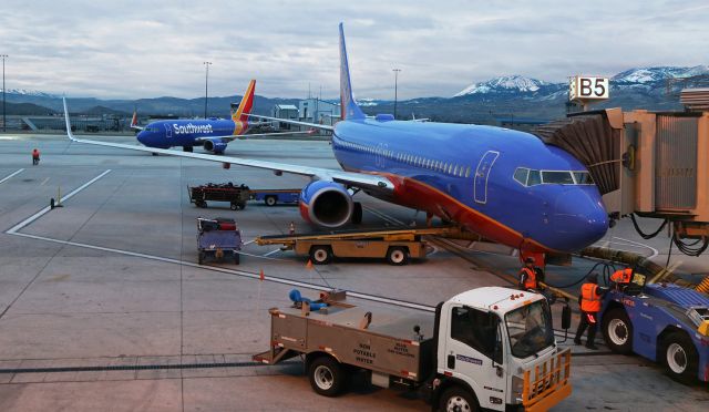 Boeing 737-800 (N8614M) - Two of the seven Southwest fleetbirds that spent the night at RNO are shown in the morning light as they are about to begin another day of flying. As N8614M is preparing to board passengers at Gate B5, another (N935WN) is off the tug and about to taxi away from the Southwest apron.