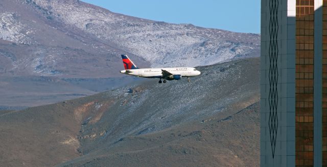 Airbus A319 (N359NB) - While on short final to runway 16R, Delta's N359NB is about to pass behind the Grand Sierra Resort. The Virginia Range Mountains located east of downtown Sparks and the airport create a nice background to the shot.