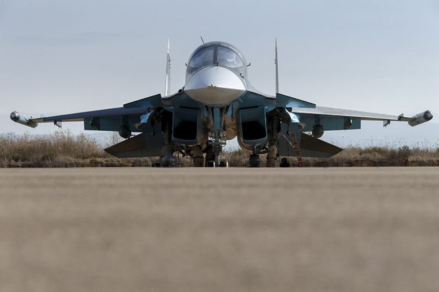 — — - Russian ground staff members work on a Sukhoi Su-34 fighter jet at the Hmeymim air base near Latakia, Syria, in this handout photograph released by Russias Defence Ministry October 22, 2015. (Photo by Reuters/Ministry of Defence of the Russian Federation)