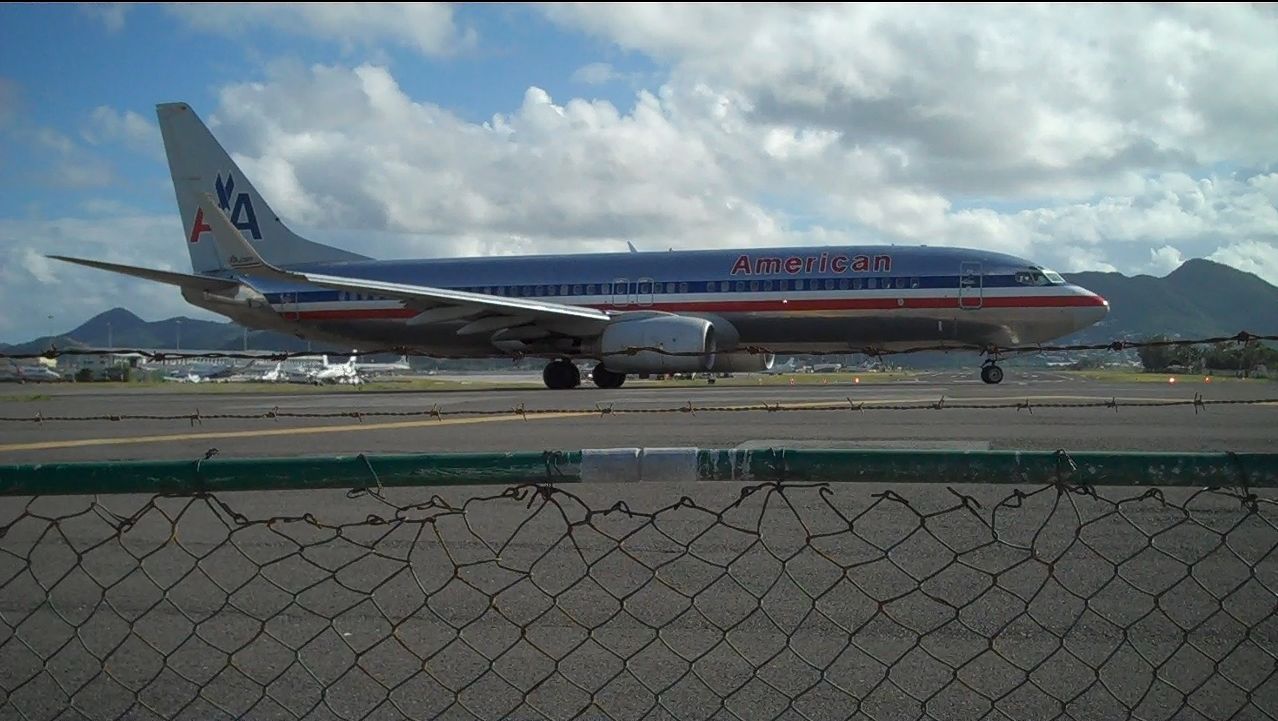 Boeing 737-800 (N975AN) - Princess Juliana International Airport (Airport Beach), A stop during my honey moon cruise. Regretfully, no larger planes were scheduled that day but this did just fine..this is a snap shot of a video I took hanging from the fence. =) I (respectfully) asked my wife if we could go there as soon as the ship docked (on the other side of 'life')...and sure enough, we were the first ones on deck at 0500. A few 'island hoppers' later, I saw this taxiing. I ran over, left hand clenched to fence, right hand with video camera and I patiently awaited being sand blasted and showered with JET A-1 fumes! Obviously, this picture or video don't do this justice, but definitely pretty friggin cool!