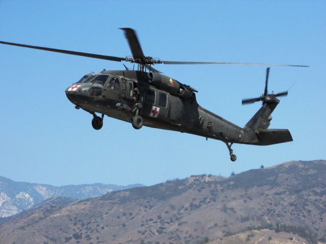 — — - Army chopper delivering patient to waiting ambulance.