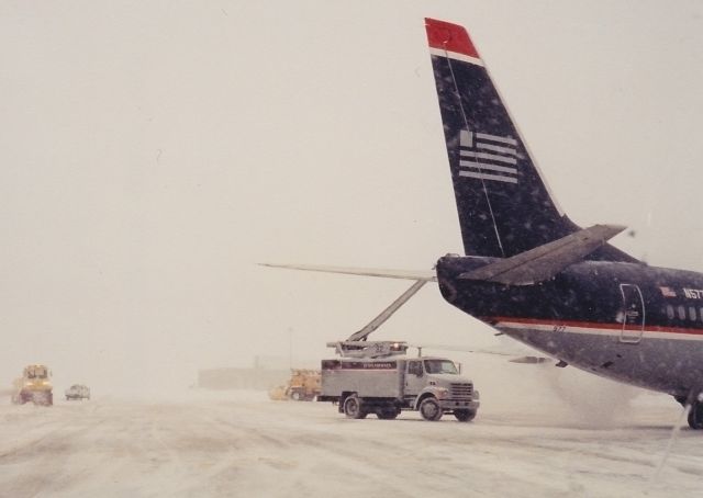 BOEING 737-300 (N577US) - Winter blast from about 15 years ago at BOS. I had a point and shoot camera in my pocket while working the deice pad on the outer taxiway at B Terminal. White out conditions looking out towards the runways...just like today! 2-8-16