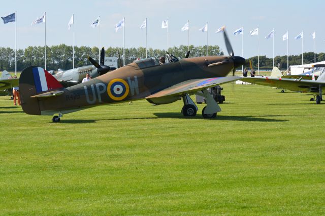 R4118 — - Hawker Hurricane passing four parked Spitfires after landing at Goodwood Airport during set up day for the Goodwood Revival Motor Race meeting on 10 Sep 2015