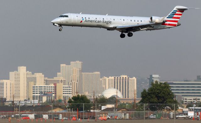 Canadair Regional Jet CRJ-700 (N748SK) - A SkyWest CRJ7 (N748SK) wearing American Eagle titles and paint passes above the boundary fence as it is about to land on 16L at the end of a midmorning flight from LAX.