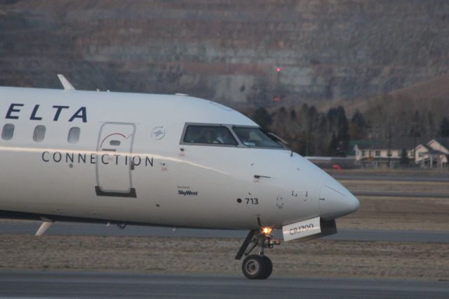 Canadair Regional Jet CRJ-700 (N713EV) - N713EV taxiing to the runway at Butte as SKYWEST 4312 to KSLC with the Berkeley Pit behind it.br /br /Taken 18:06, November 2, 2024 with a Canon EOS T2i and 70-300mm (300mm, 1/400, ƒ7.1, ISO 3200)