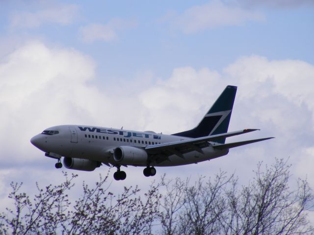 Boeing 737-700 (C-GWSJ) - just clearing the trees on the approach to #32