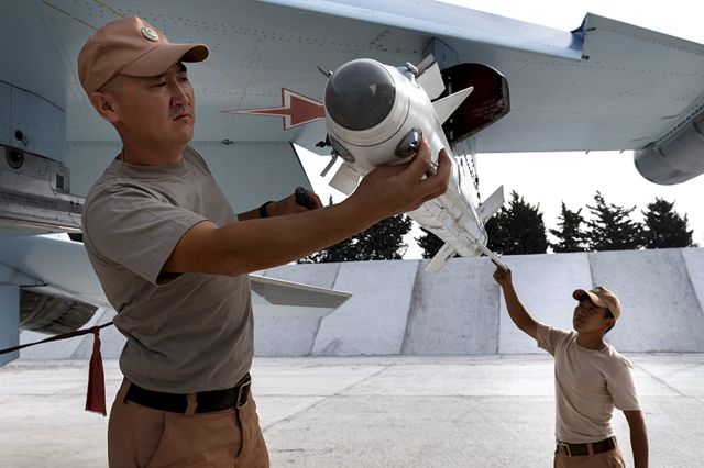 — — - Russian ground staff members load a Sukhoi Su-30 fighter jet with weapons at the Hmeymim air base near Latakia, Syria, in this handout photograph released by Russias Defence Ministry October 22, 2015. (Photo by Reuters/Ministry of Defence of the Russian Federation)